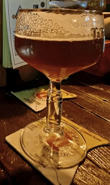 Cáliz de cristal con pie, ancho y de boca abierta, con cerveza ámbar y una capa fina de espuma